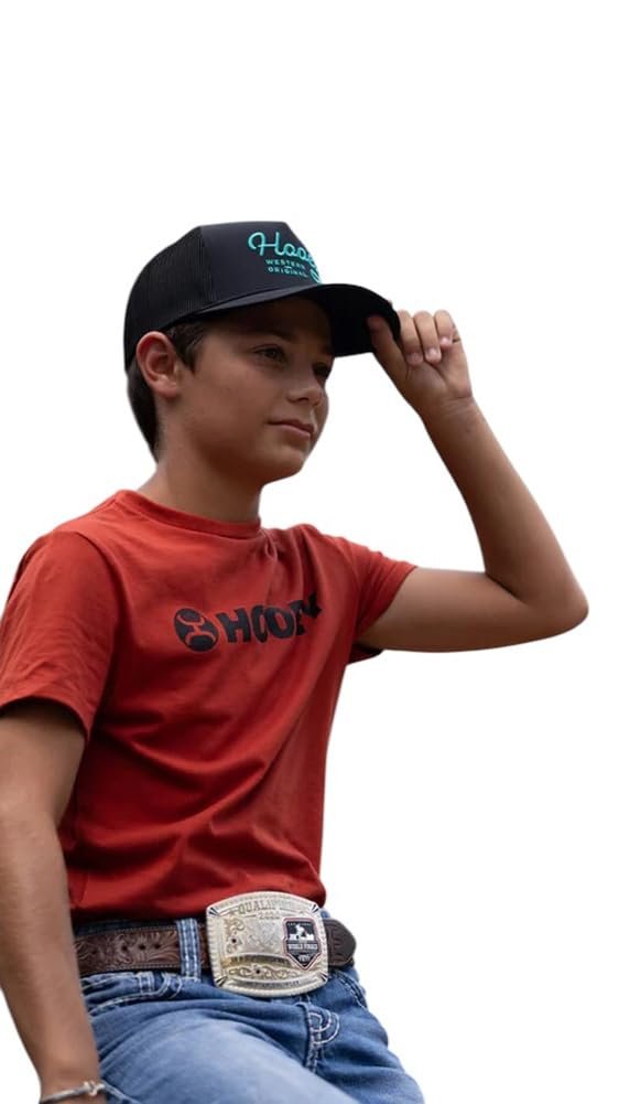 Child wearing a red shirt and blue jeans with a black cap on a white background