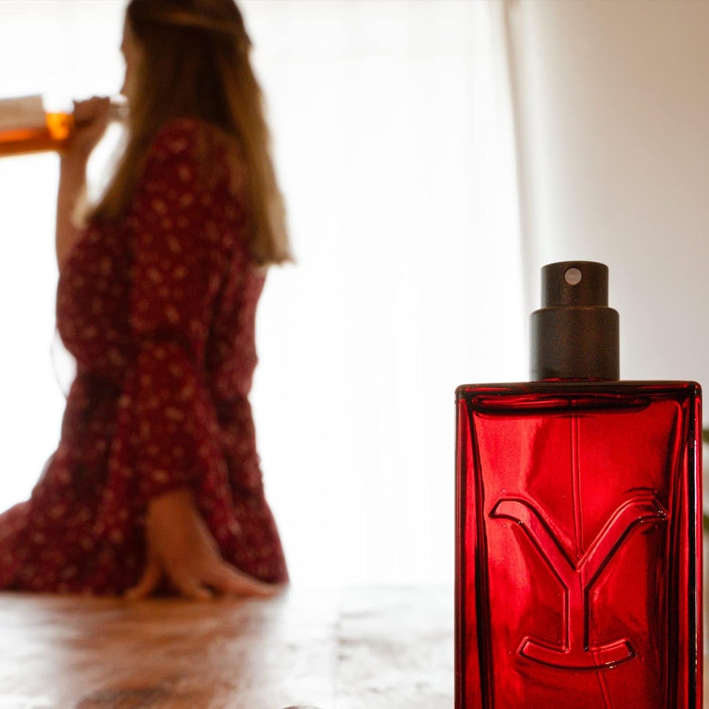 Bottle of Women's Yellowstone Tornado Perfume by Tru Western With Woman in the Background Holding Alcohol Bottle