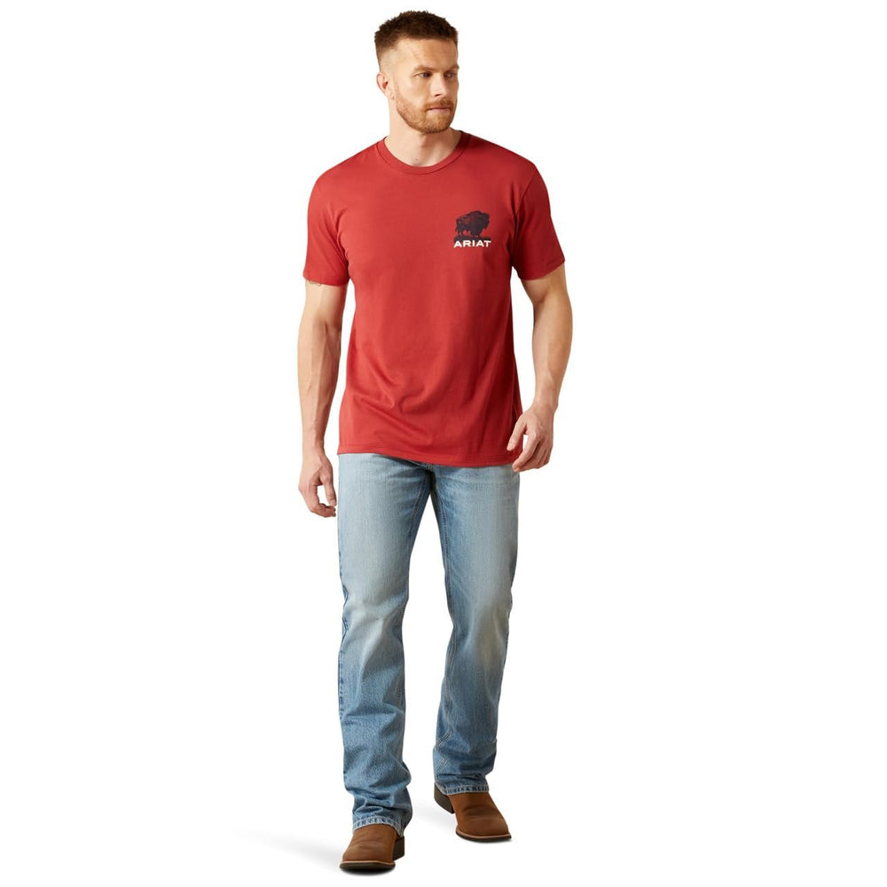 
                  
                    Man wearing a red t-shirt with a logo and blue jeans on a white background
                  
                