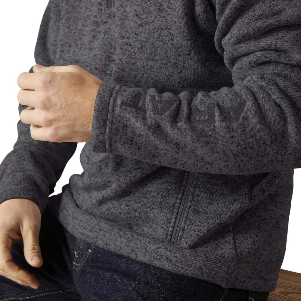 
                  
                    Person wearing a dark gray fleece jacket with a close-up of the sleeve and zipper area.
                  
                