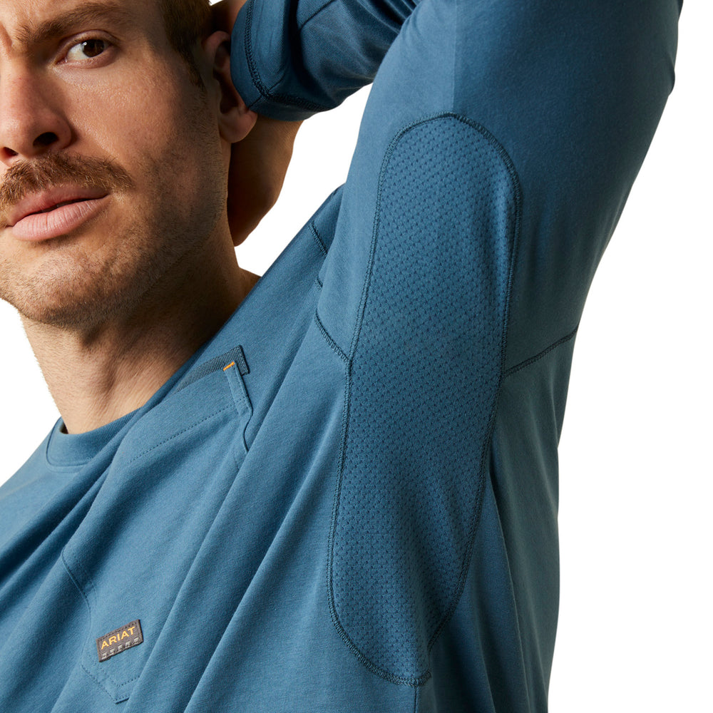 
                  
                    Man wearing a blue long-sleeve shirt with a brand logo on a white background
                  
                