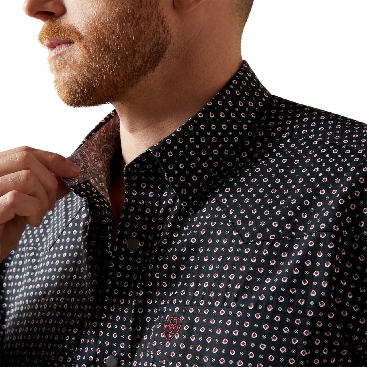 Man wearing a dark patterned shirt with a close-up of the collar.