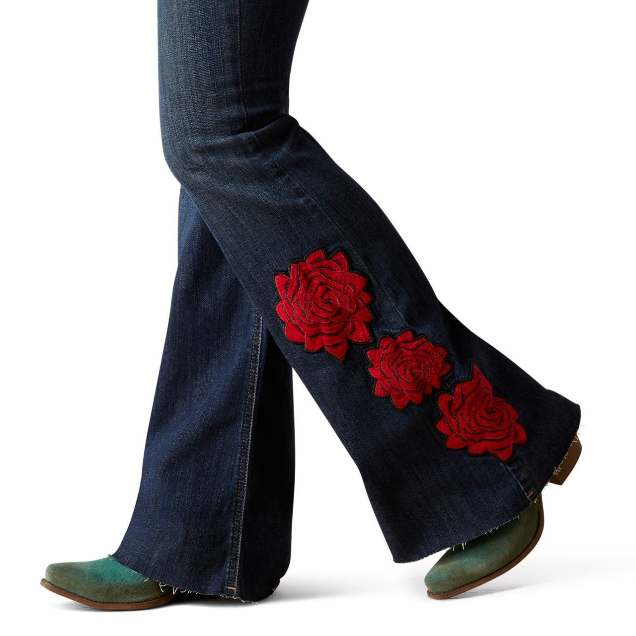 Blue jeans with red floral patches worn by a person on a white background