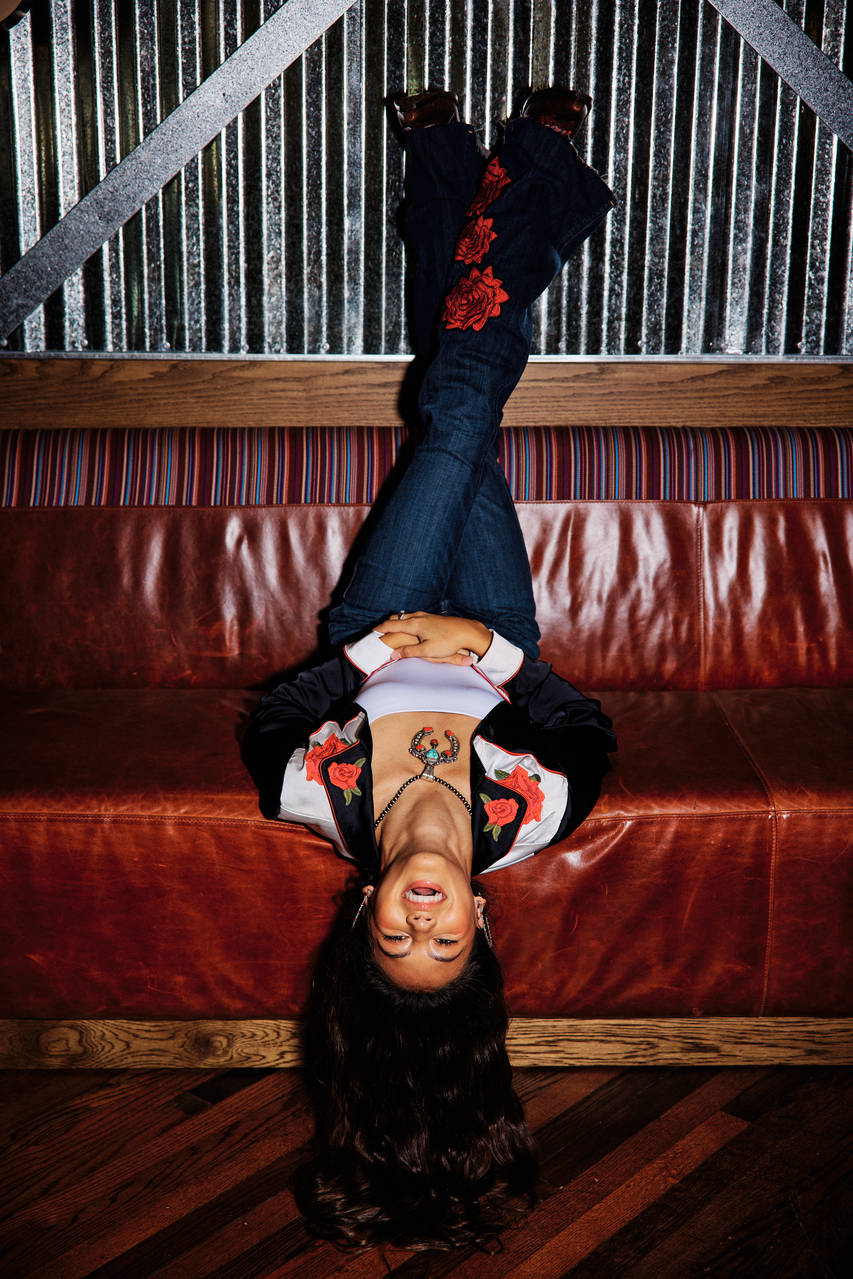 Person lying on a red leather couch with a patterned wall in the background
