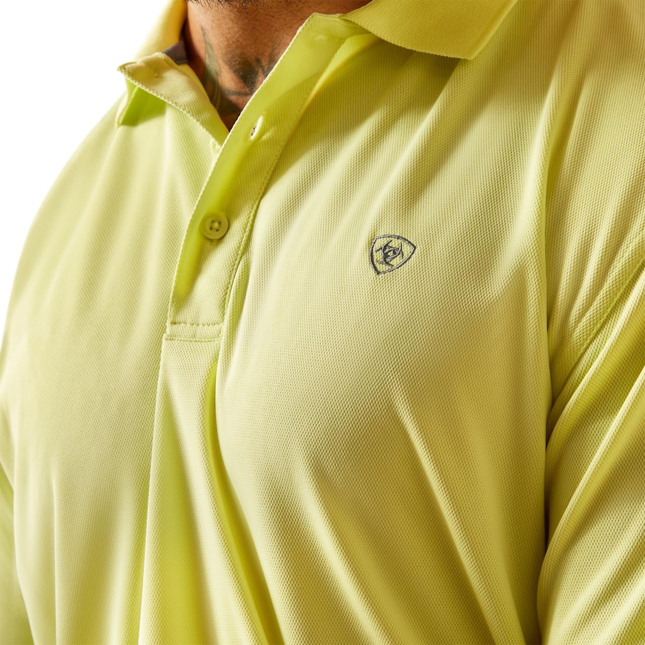 Close-up of a light green polo shirt with a logo on the chest.