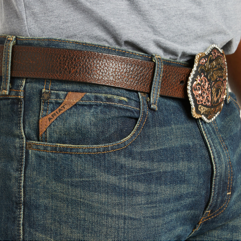 
                  
                    Close-up of blue jeans with a brown leather belt and decorative buckle.
                  
                