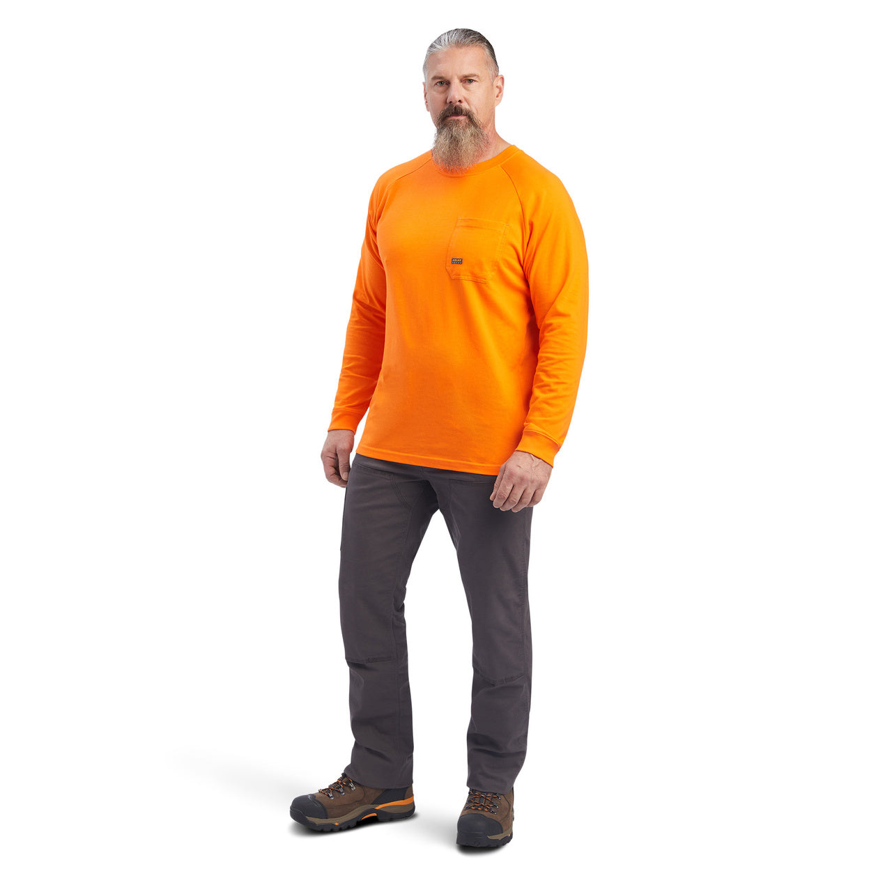 Man wearing an orange long-sleeve shirt and gray pants on a white background