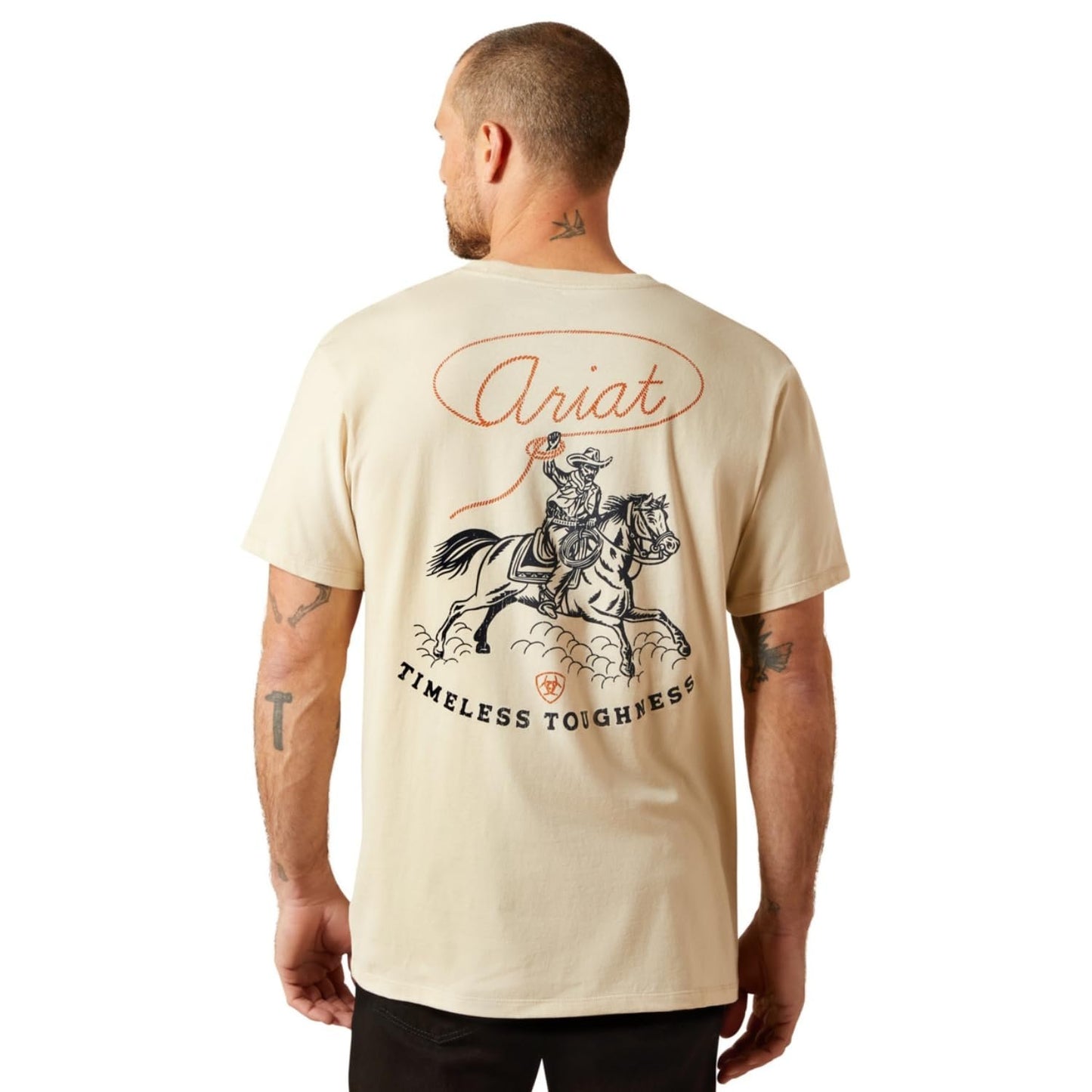Man wearing a beige t-shirt with Ariat branding and graphic design on the back.