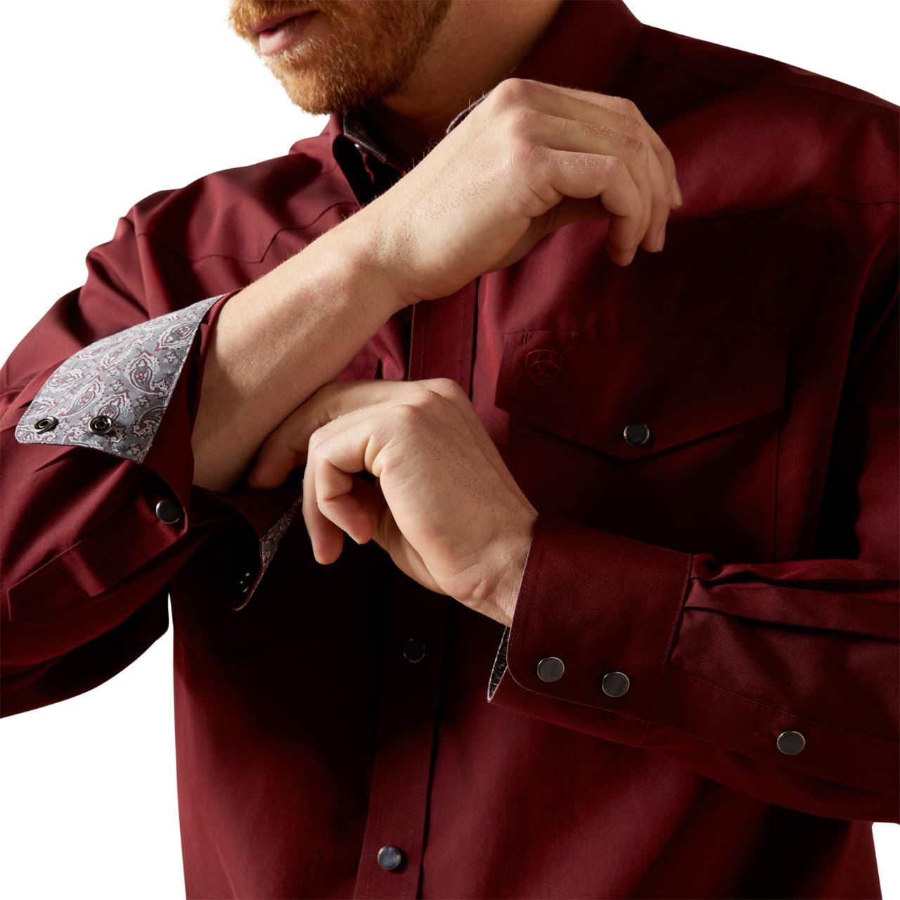 Person wearing a burgundy jacket with silver buttons and cuffs on a white background