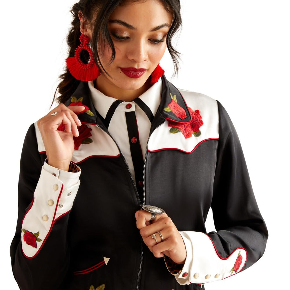 Woman wearing a black and white jacket with red floral embroidery on a white background