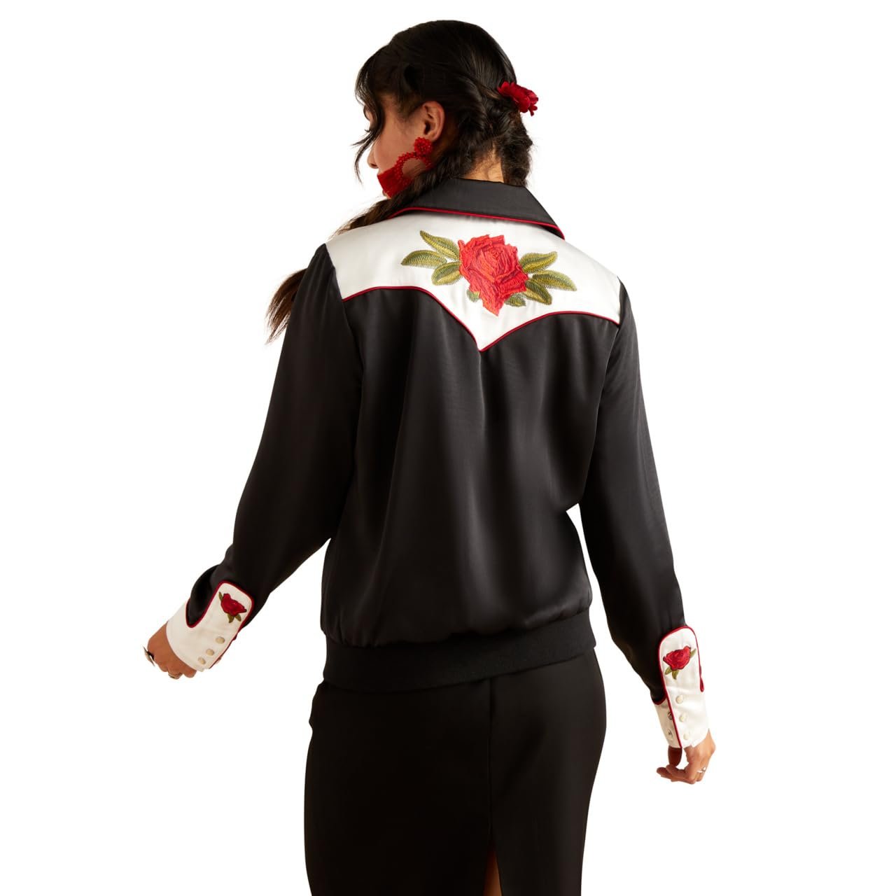 Person wearing a black outfit with white accents and red floral embroidery on a white background