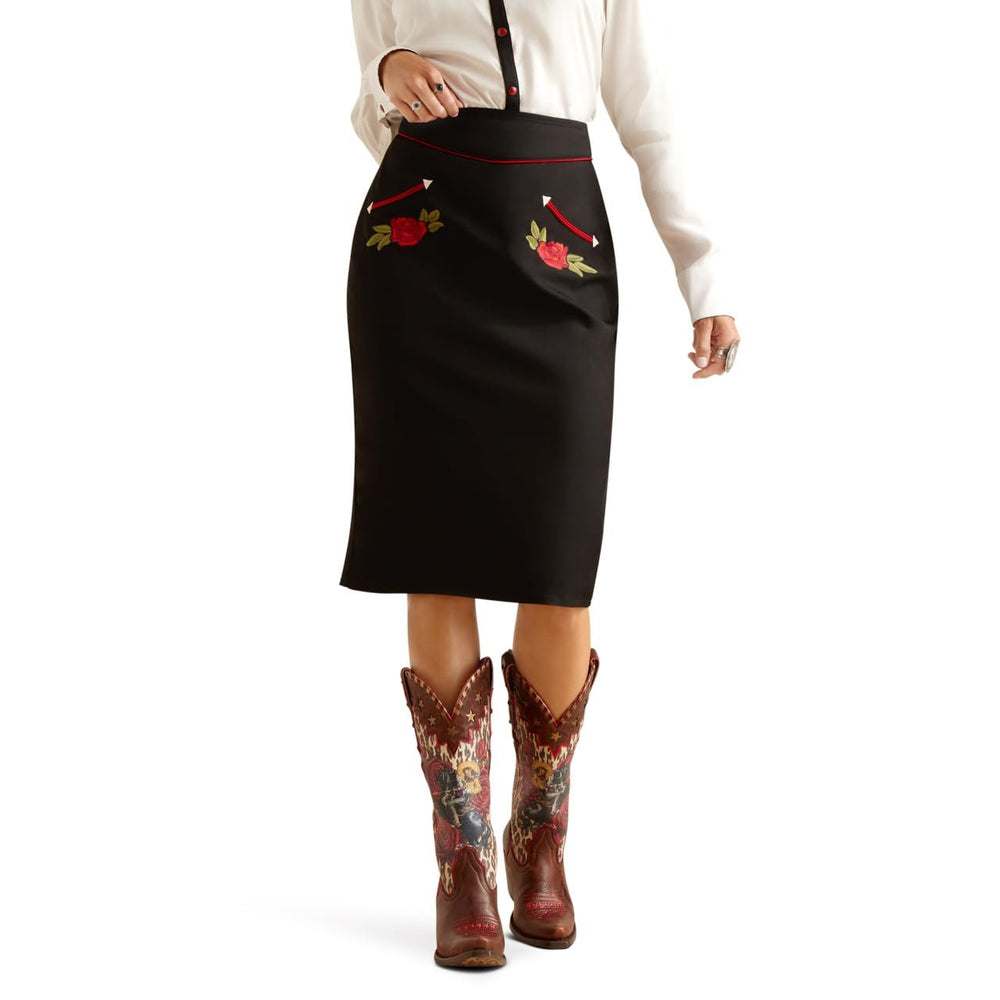 
                  
                    Person wearing a black skirt with floral embroidery and brown boots on a white background
                  
                