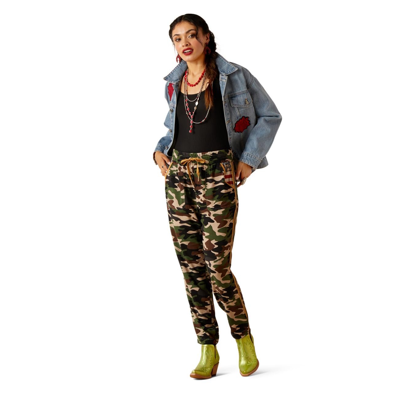 Woman wearing a denim jacket, black top, and camouflage pants on a white background