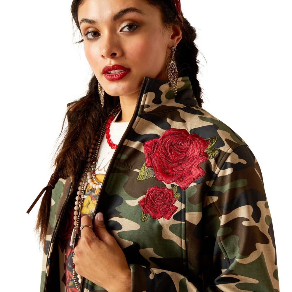 
                  
                    Woman wearing a camouflage jacket with red floral embroidery on a white background
                  
                
