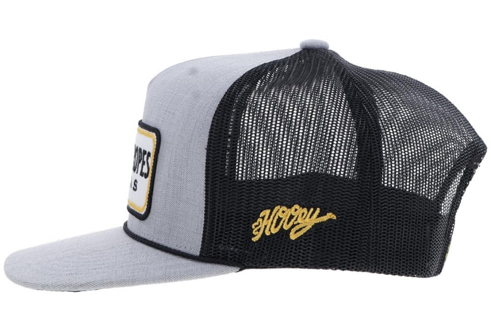 Trucker hat with gray front panel, black mesh back, and yellow logo on a white background