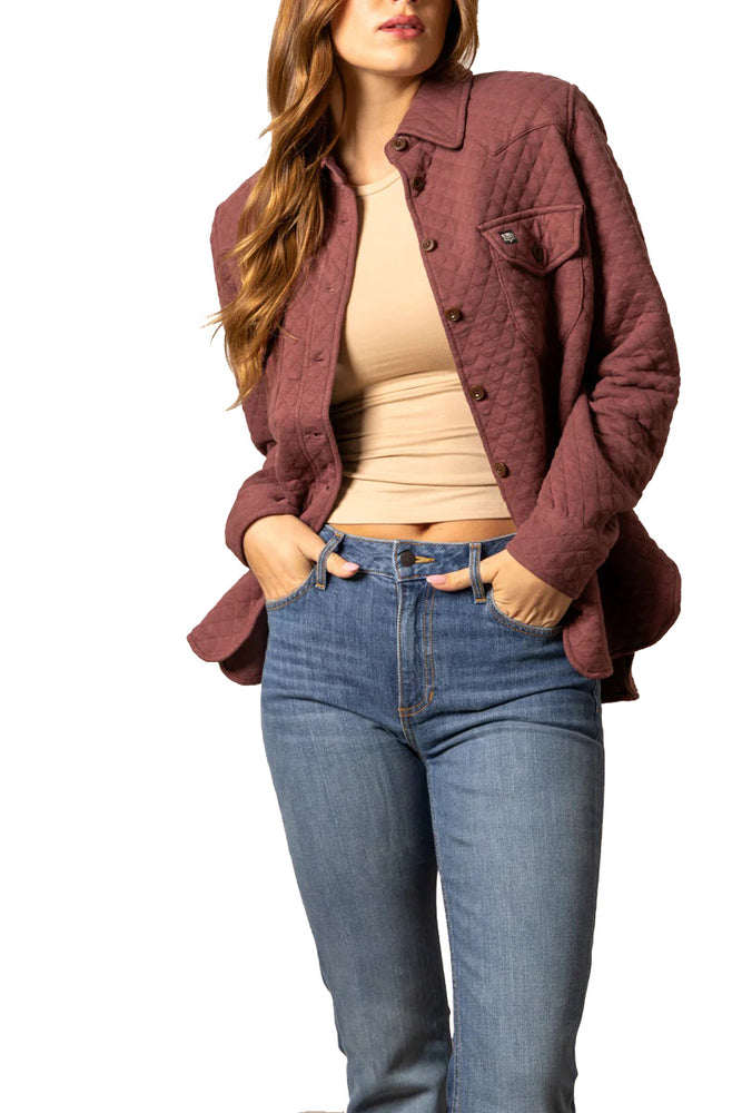 
                  
                    Woman wearing a burgundy jacket, beige top, and blue jeans on a white background
                  
                