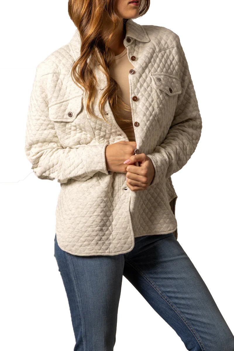 Woman wearing a beige quilted jacket and blue jeans on a white background
