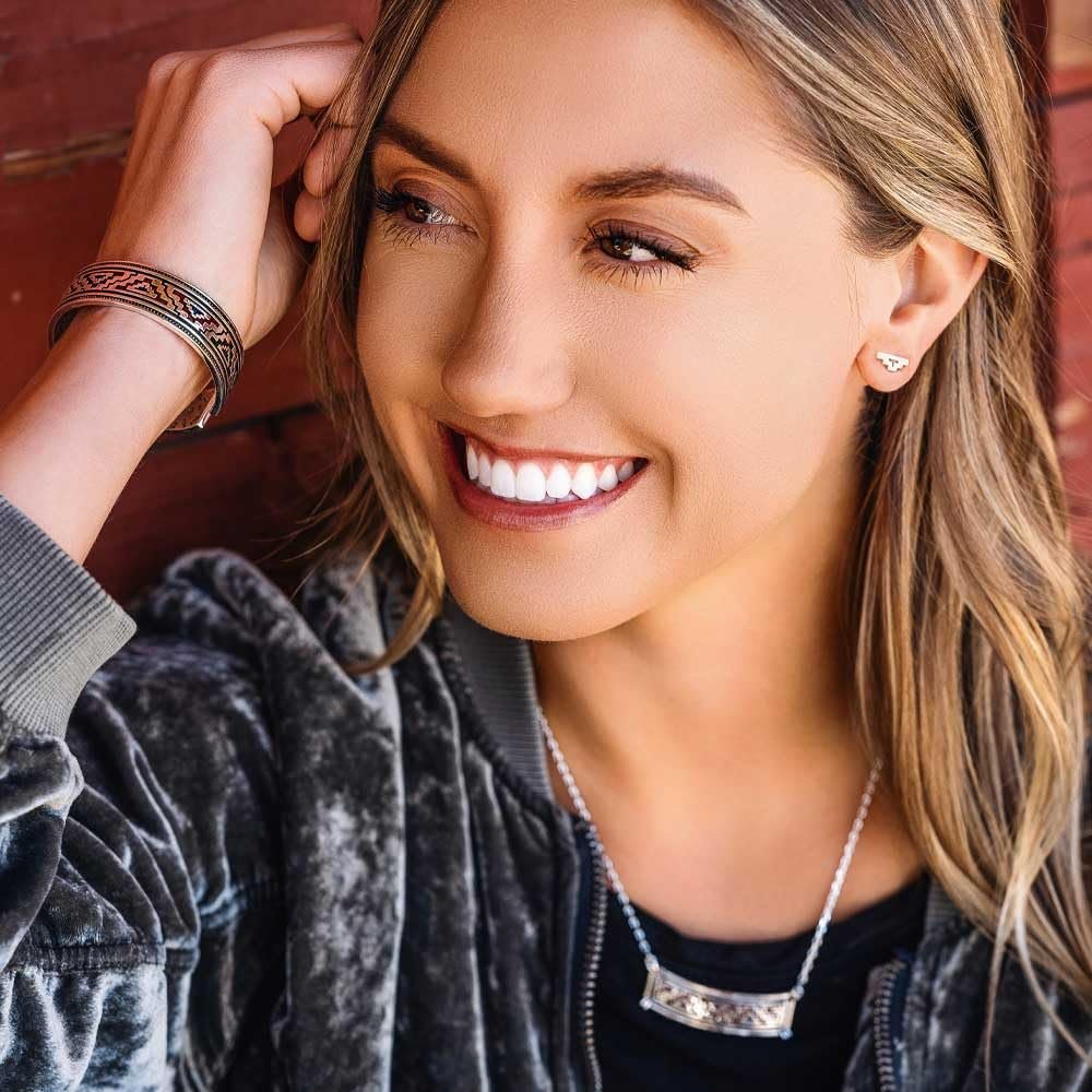 
                  
                    Woman with a smile wearing a gray jacket and a necklace.
                  
                