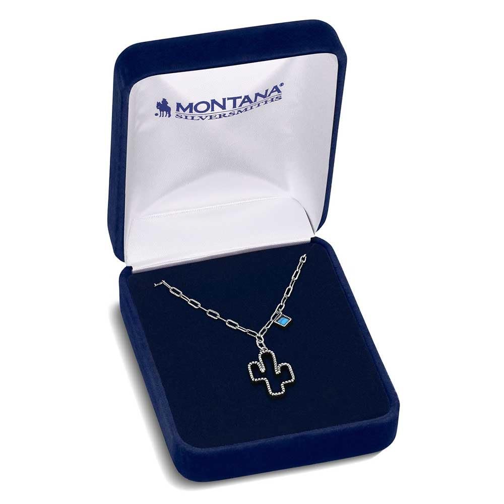 
                  
                    Jewelry box with a necklace featuring a cross pendant and blue gemstone, branded 'Montana Silversmiths'.
                  
                