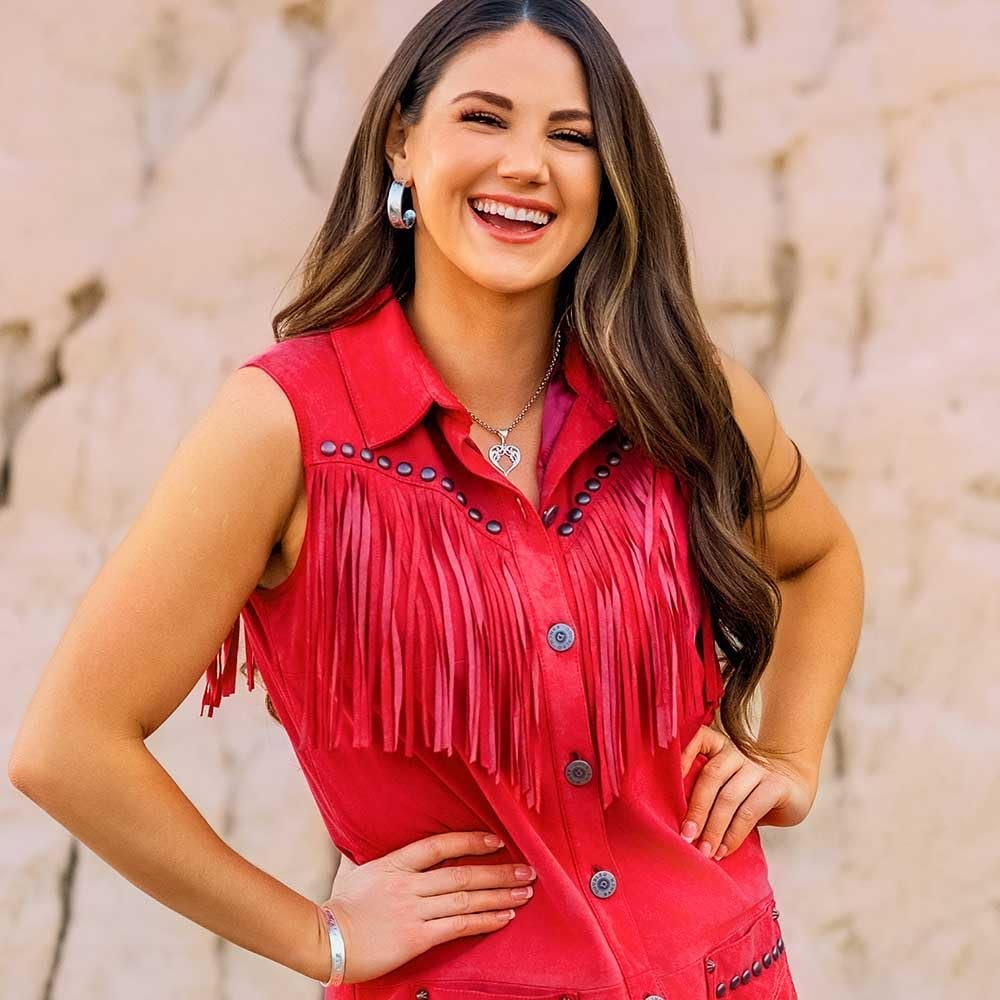 
                  
                    Woman wearing a red fringed vest against a stone wall background
                  
                