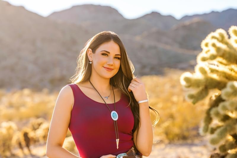 
                  
                    Woman in a red top standing in a desert with cacti and mountains in the background
                  
                