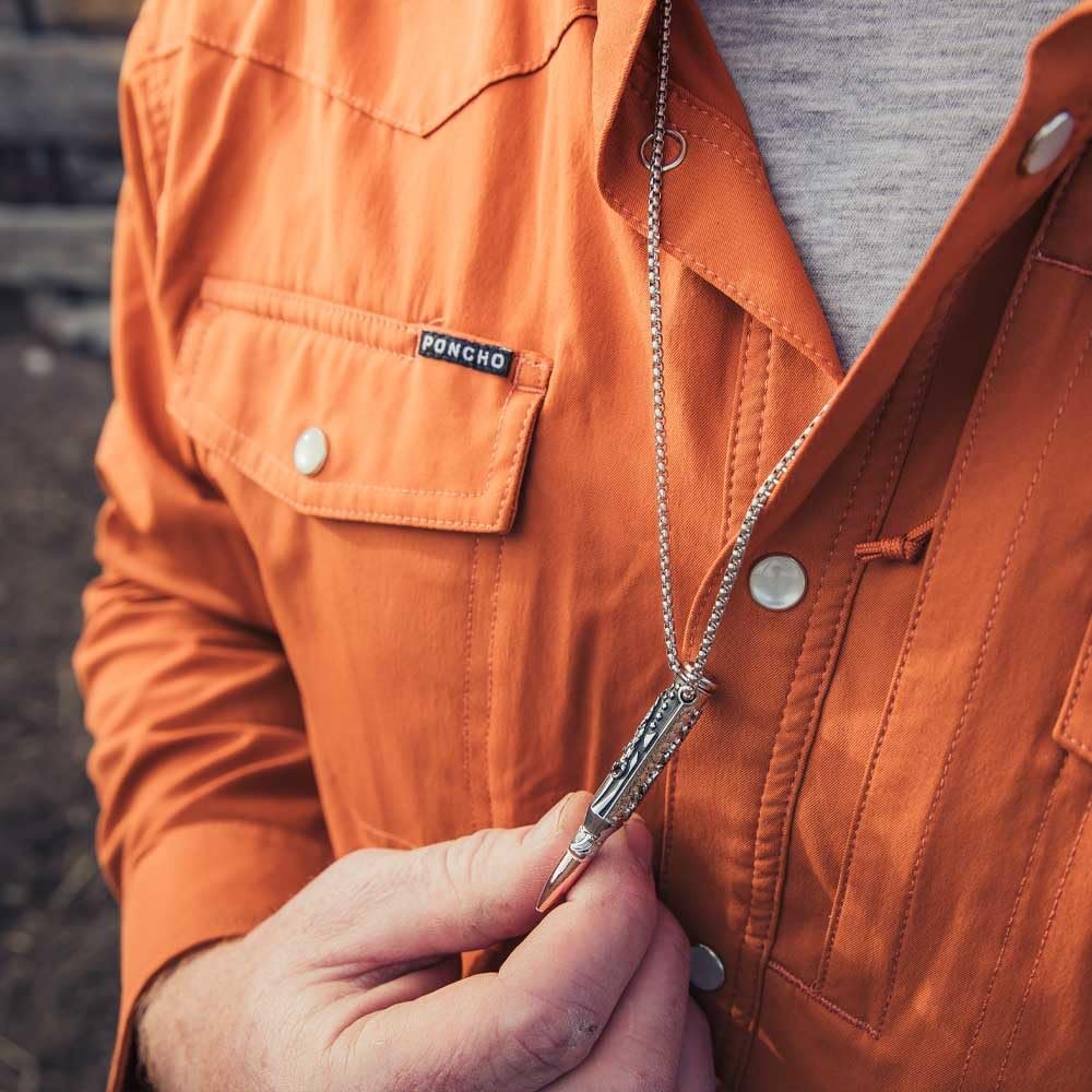 
                  
                    Person wearing an orange jacket with a 'Poncho' label, holding a silver pocket knife.
                  
                