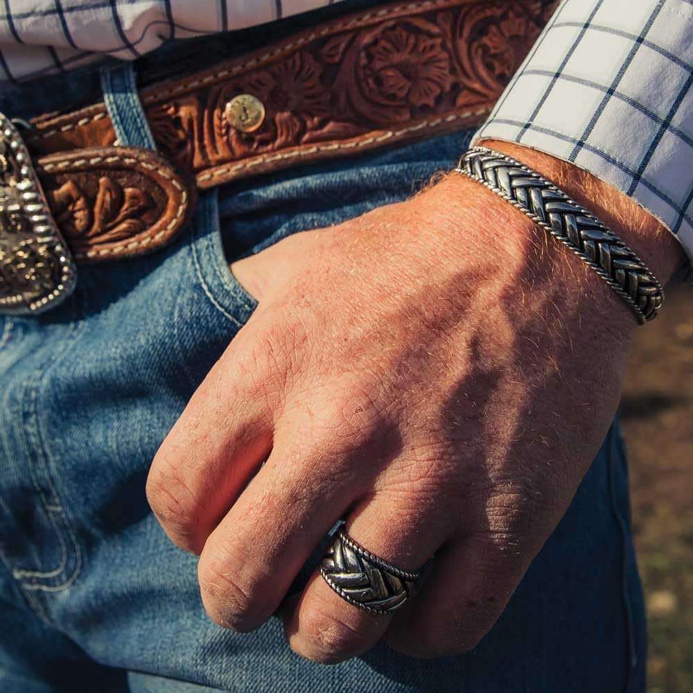 
                  
                    Close-up of a hand wearing a silver ring with a textured band, against a background of blue jeans and a brown leather belt.
                  
                