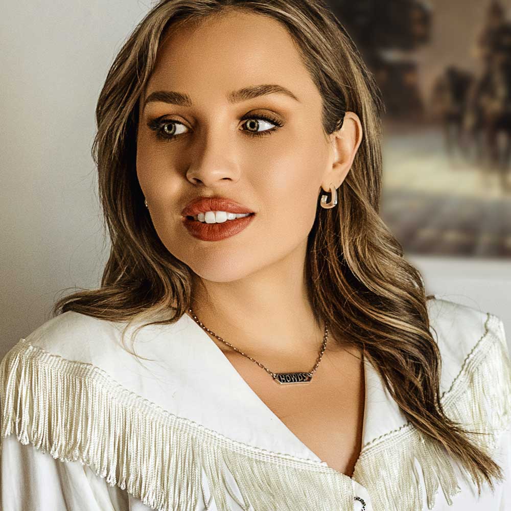 Woman wearing a white fringed garment with a neutral background
