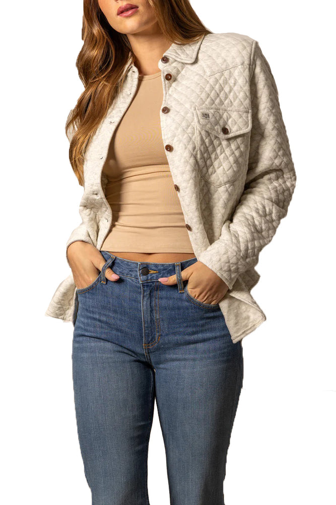 
                  
                    Woman wearing a beige quilted jacket, beige top, and blue jeans on a white background
                  
                