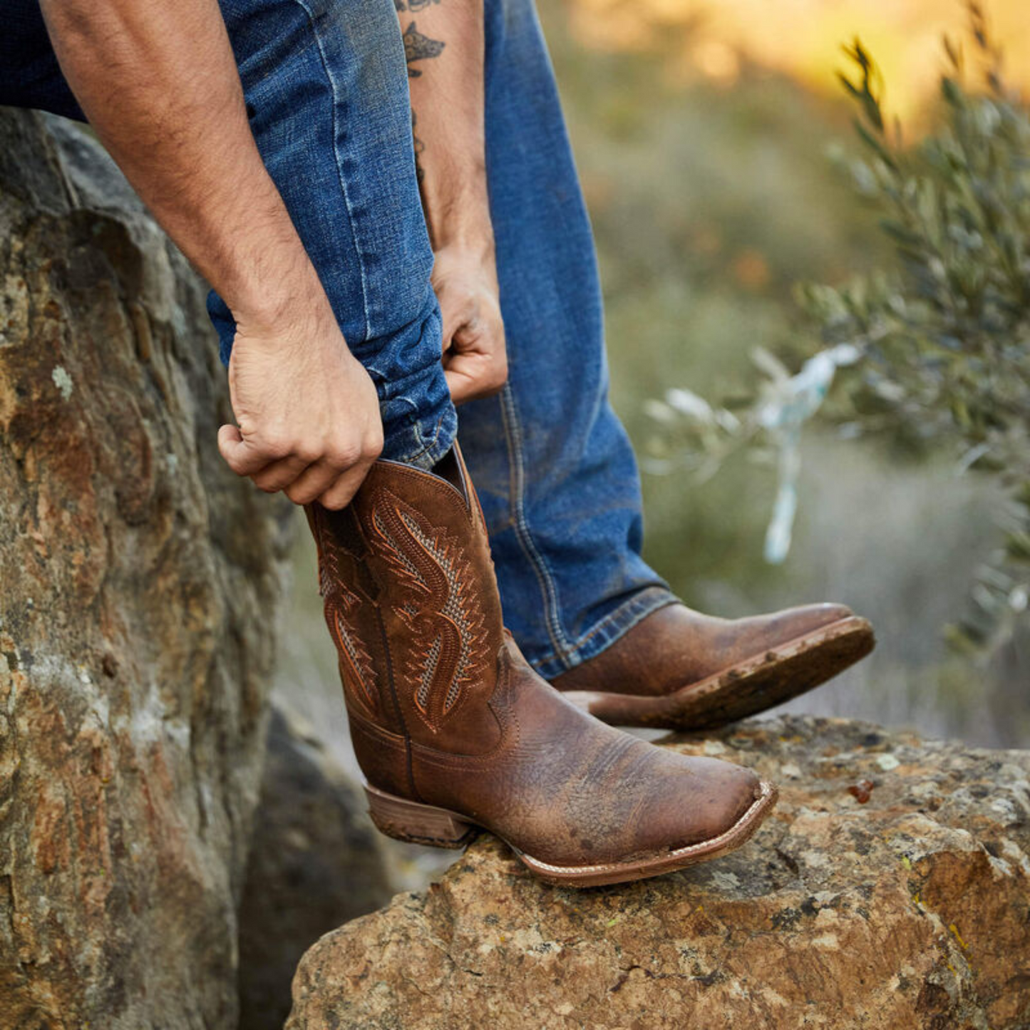 Man pulling up Ariat cowboy boots
