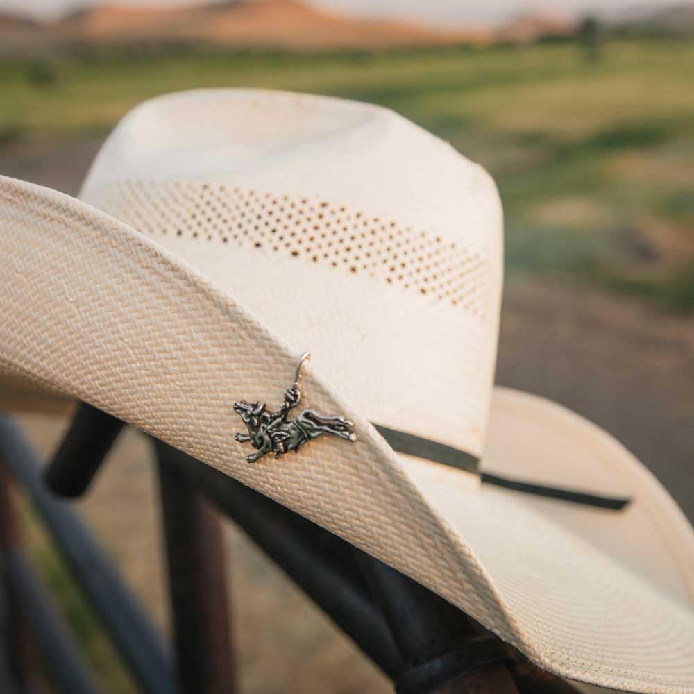 
                  
                    Hat with Rider’s Resolve Hat Clip attached. A straw cowboy hat with the bull rider hat clip fastened to the brim, adding a touch of Western style
                  
                