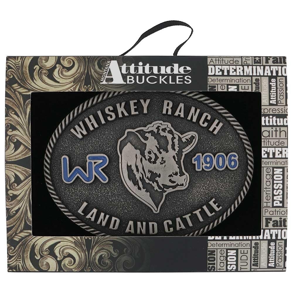 
                  
                    Whiskey Ranch Western Belt Buckle in packaging – The western belt buckle displayed in its Montana Silversmiths "Attitude Buckles" packaging, featuring intricate gold scrollwork and branding elements.
                  
                