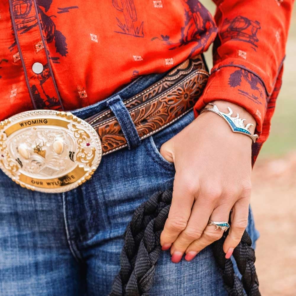 
                  
                    Person wearing a red shirt with blue patterns, blue jeans, and a decorative belt buckle, with the High Country Opal Ring
                  
                