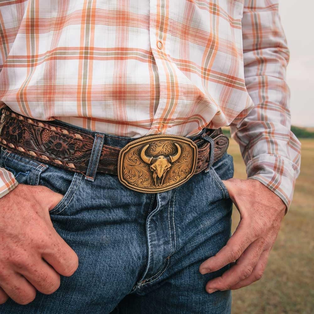 
                  
                    Cowboy wearing the Wild Ambition Western Belt Buckle with a buffalo skull design, styled with jeans and a plaid shirt.
                  
                