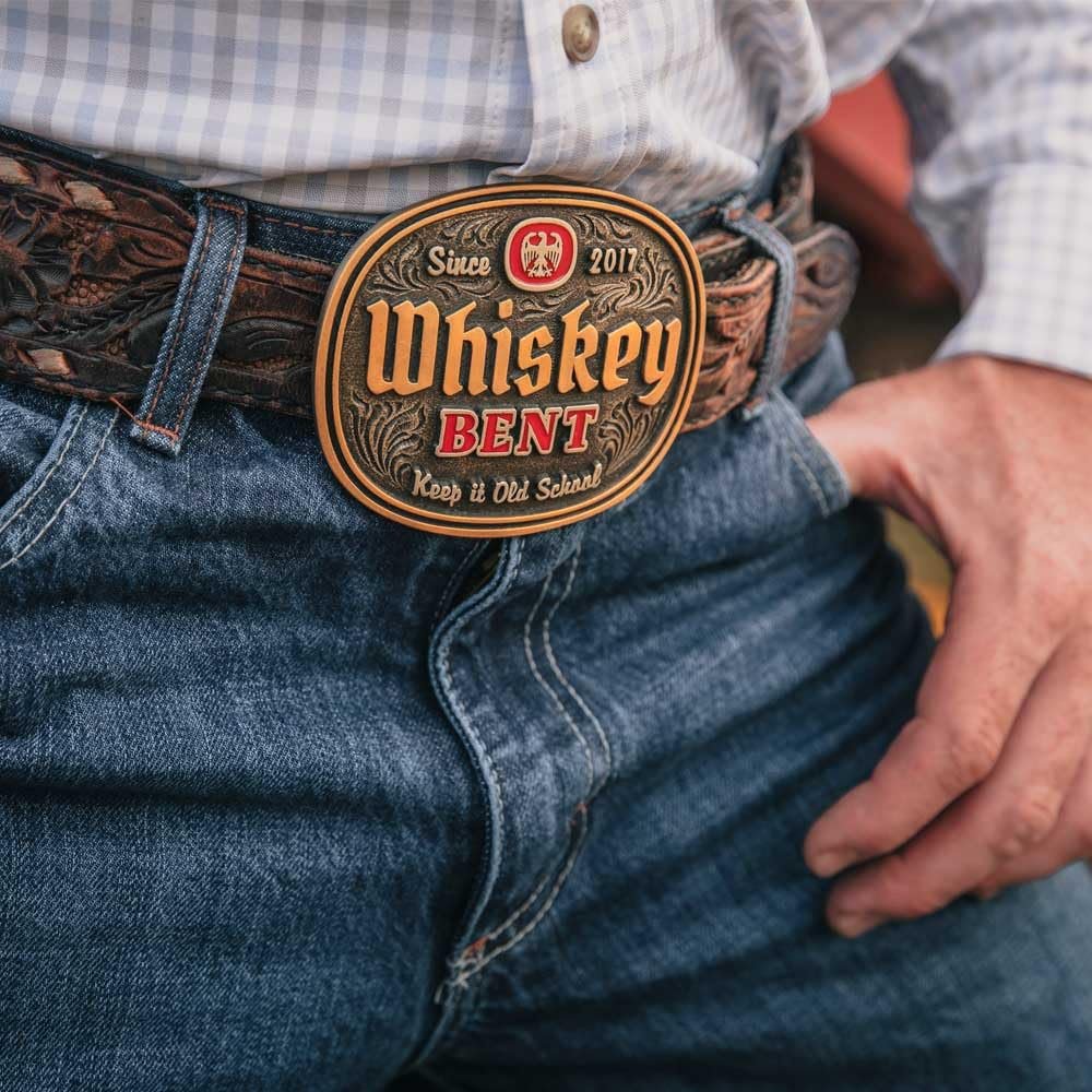 
                  
                    Man wearing the Whiskey Bent Western Belt Buckle – A cowboy in blue jeans and a Western belt showcasing the Whiskey Bent belt buckle, styled with a plaid button-up shirt.

                  
                
